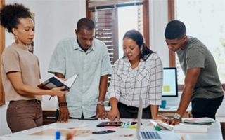 Group of four brainstorming over a table covered with miscellaneous items