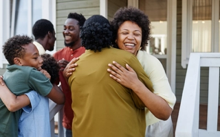 Happy family hugging and smiling seeing each other in front of their home