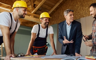 Group of construction workers discussing and reviewing blueprints
