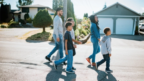 Happy family of five taking a stroll on a sunny day through their neighborhood