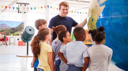 Group of young students observing a oversized globe