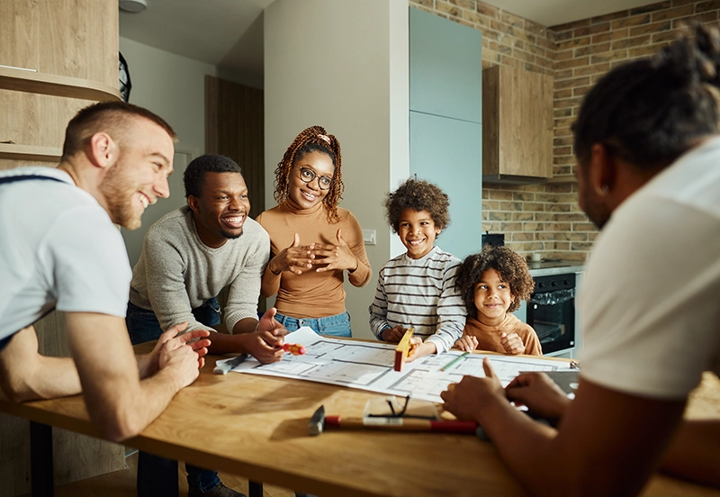 Happy black family talking to manual workers about housing plans in the apartment.