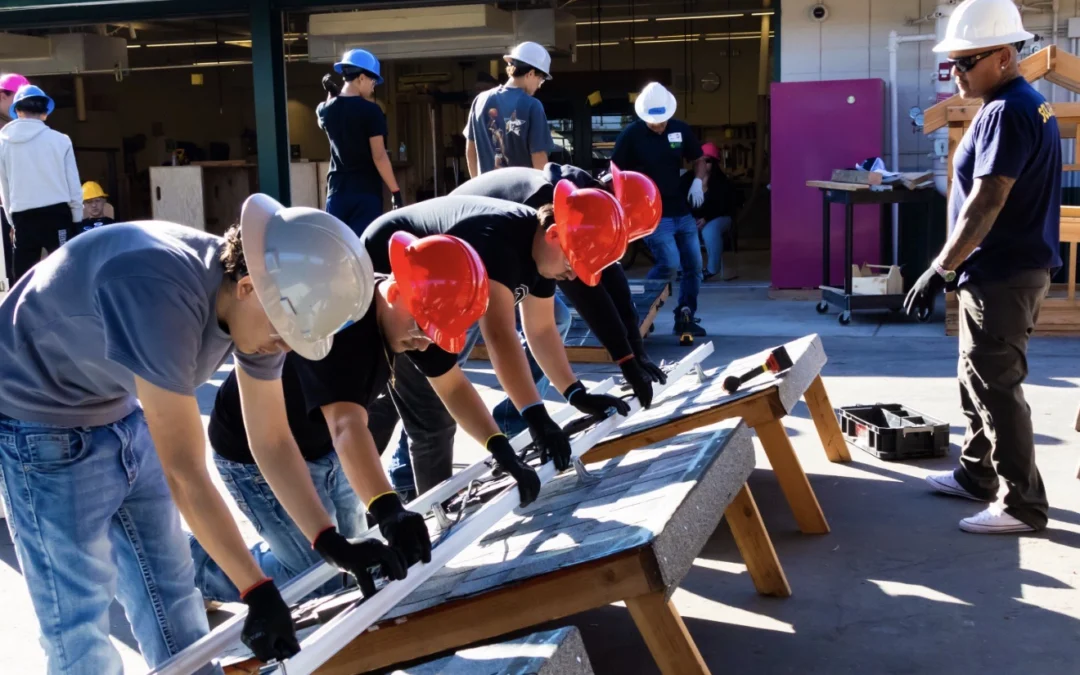 Group of construction apprentices leveling a rail with lead instructor observing