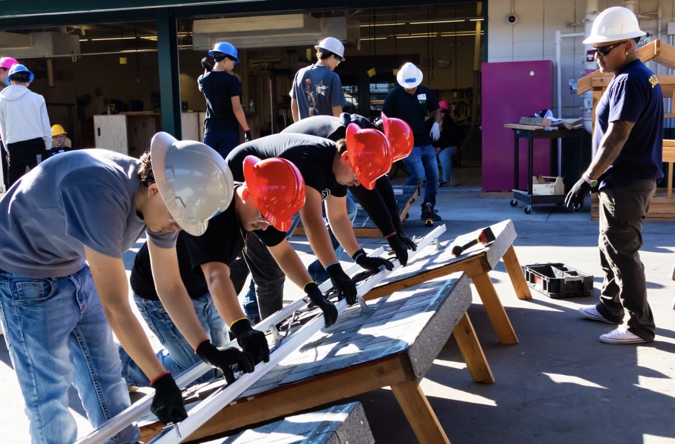Group of construction apprentices leveling a rail with lead instructor observing