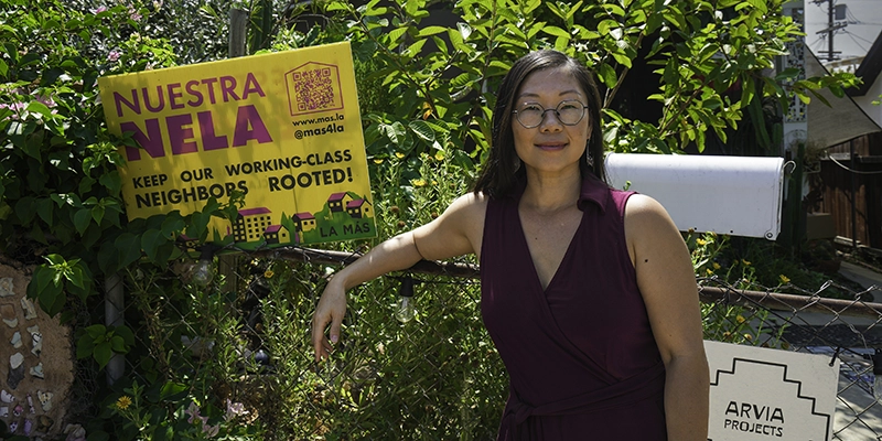 Helen Leung of LA Más posing next to a yellow Nuestra Nela Sign
