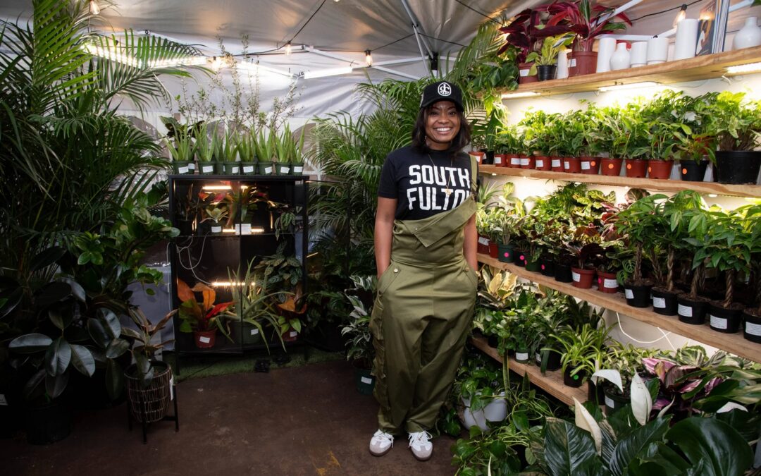 Crystal Thomas of Tropical Express surrounded by plants and greenery inside her boutique